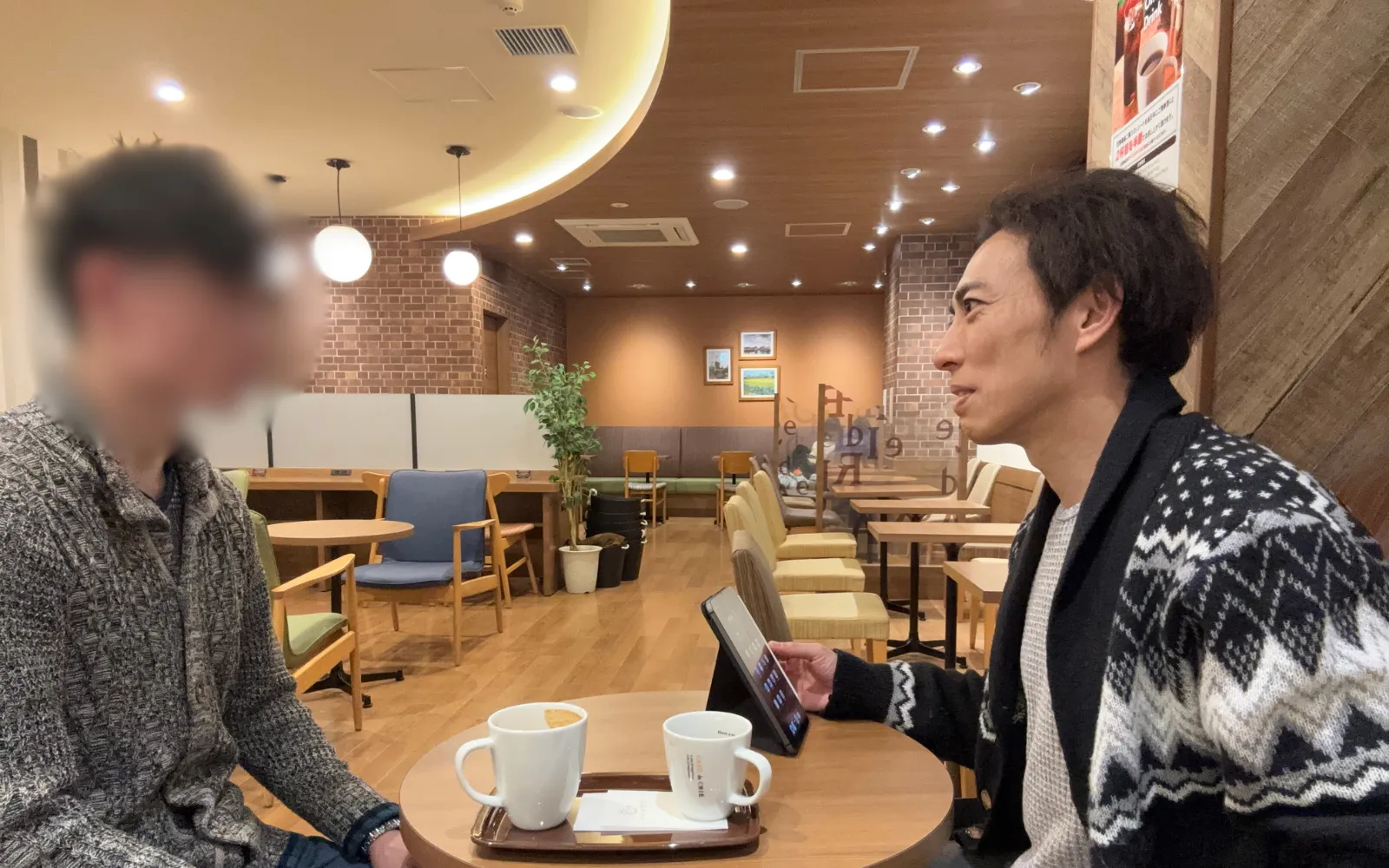 カフェでタブレットを見ながら打ち合わせをするほっともっとオーナーのイメージ