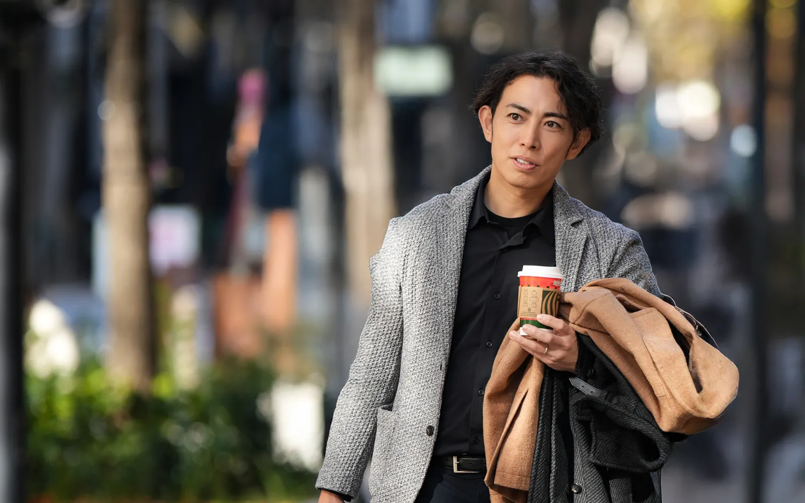 コーヒーを片手に考え事をしながら一人で歩くほっともっとオーナーのイメージ