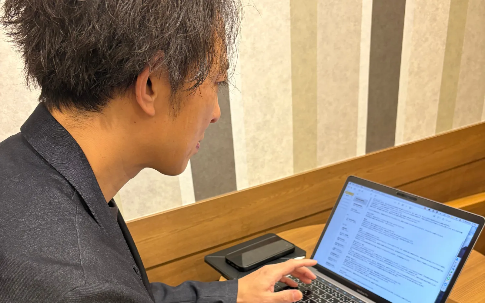 PCに向かってブログを書きながら振り返るほっともっとオーナーのイメージ